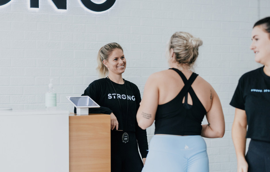 Staff member welcoming two members at the front desk